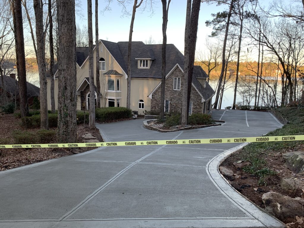 A large house near a lake with a newly paved driveway is blocked off by yellow caution tape.