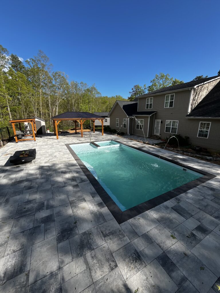 stone patio surrounded by trees. Nearby, a wooden pergola complements the gray house