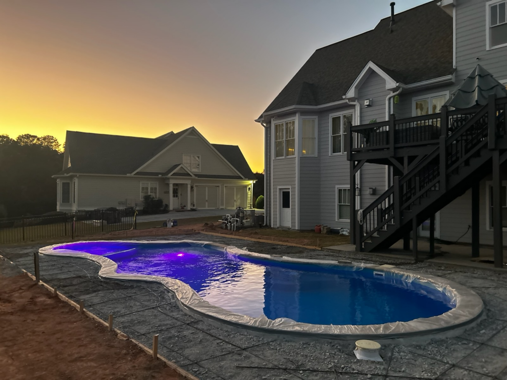 rounded fiberglass pool with concrete patio under construction