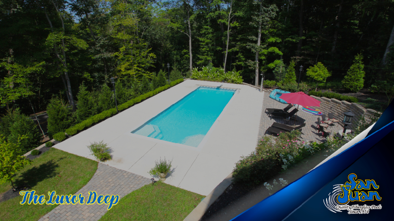 A rectangular outdoor swimming pool is surrounded by a concrete deck, lounge chairs, umbrellas, and greenery, with trees in the background. The text reads “The Luxor Deep.”.